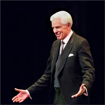 photo of Anthony Morss, an older, white-haired gentleman in a tuxedo, half-bowing to left